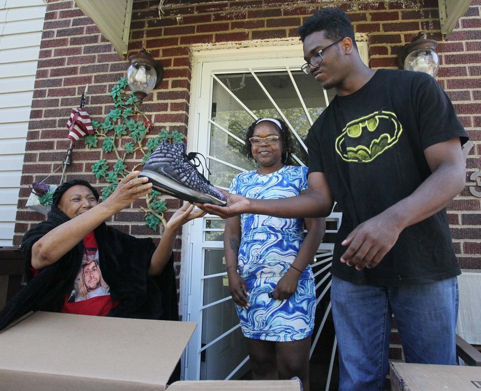 Rebecca Shepard, left, hands a shoe that belonged to her late son, Wesley Shepard, to her son Jayson Lockett as her niece Jessica Lockett watches.