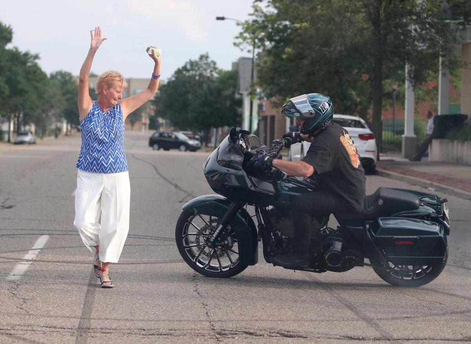 Janine Nesselhauf, Matthew Parisi's mother, stands in the center of North Main Street as motorcyclist Jeff "C-Bear" Flaherty does burnouts around her in tribute to Parisi after calling hours Sunday at Hennessy-Bagnoli-Moore Funeral Home in Akron.