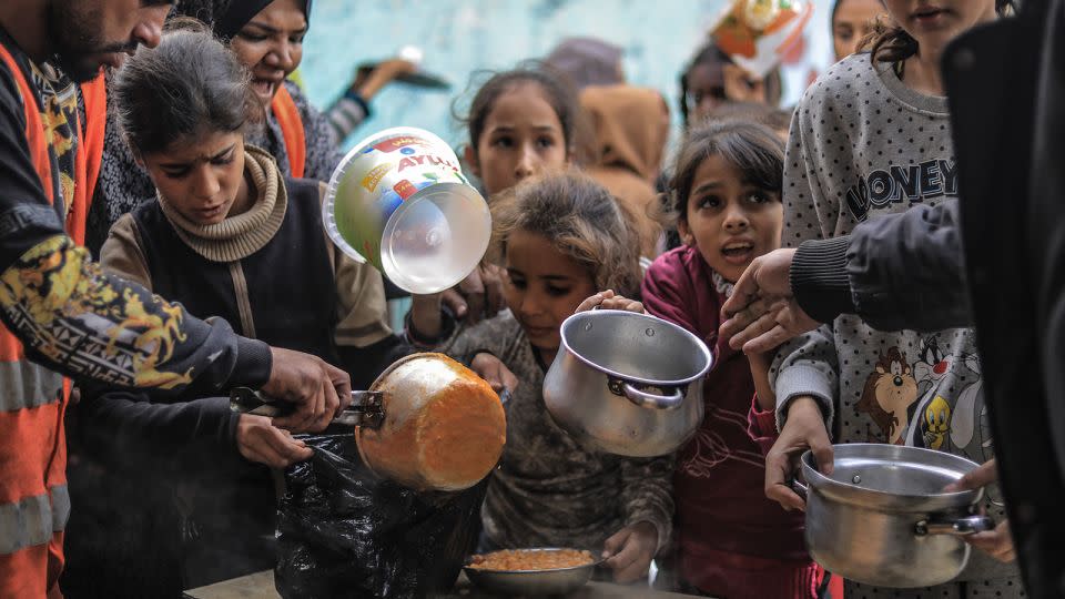 Displaced Palestinians gather to collect food cooked by volunteers in Rafah on December 9, 2023. - Stringer/picture alliance/dpa/Getty Images