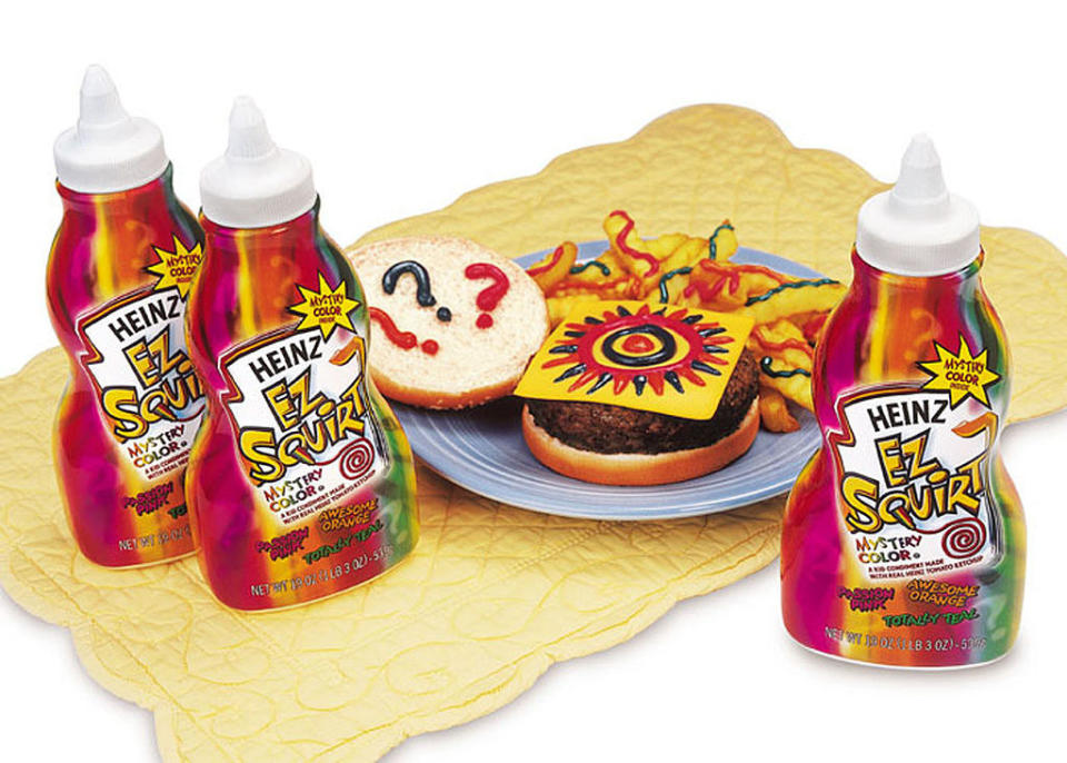 Bottles of Heinz EZ Squirt Mystery Color Ketchup next to a burger and fries