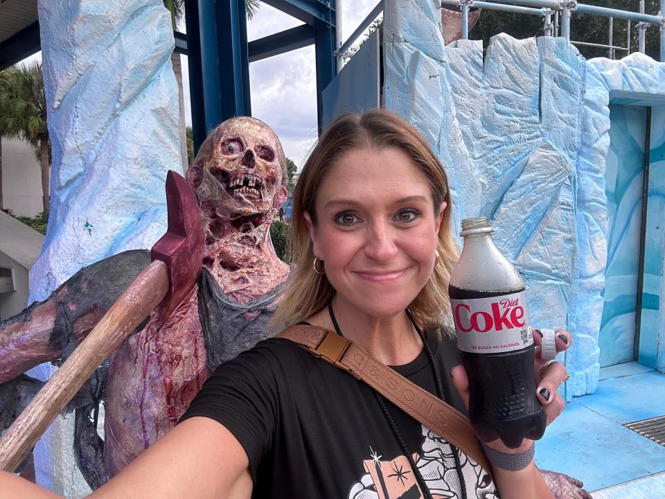 The author holding a bottle of diet coke in front of a skeleton.