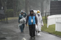 Volunteers walk in the rain after the second round of the Zozo Championship PGA Tour is postponed due to heavy rain at the Accordia Golf Narashino country club in Inzai, east of Tokyo, Japan, Friday, Oct. 25, 2019. (AP Photo/Lee Jin-man)