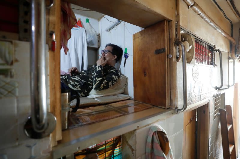 Simon Wong, 64, smokes a cigarette at his 2 square metre subdivided residential unit, known as a "coffin home", following the outbreak of the new coronavirus, in Hong Kong, China February 17, 2020. Picture taken February 17, 2020. REUTERS/Tyrone Siu