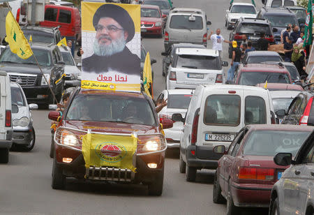 A man gestures as he drives a car with the picture of Hezbollah leader Sayyed Hassan Nasrallah on it, during the parliamentary election day, in Bint Jbeil, southern Lebanon May 6, 2018. REUTERS/Aziz Taher