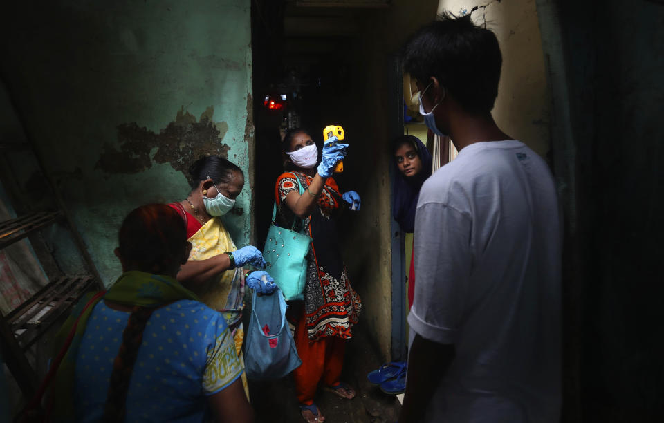 FILE - In this July 6, 2020, file photo, a health worker screens people for COVID-19 symptoms at Dharavi, one of Asia's biggest slums, in Mumbai, India. A new snapshot of the frantic global response to the coronavirus pandemic shows some of the world's largest government donors of humanitarian assistance are buckling under the strain and overall aid commitments have dropped by a third from the same period last year. (AP Photo/Rafiq Maqbool, File)