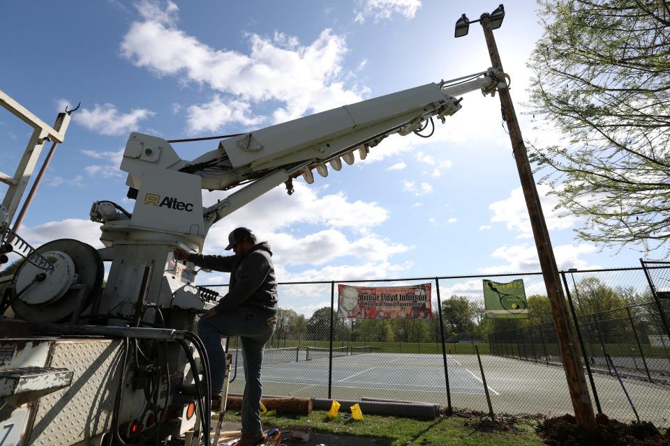 A crew replaces utility poles outside the tennis courts at Chickasaw Park in Louisville, Ky. on Apr. 17, 2023.   A shooting over the weekend killed two and injured four others.  