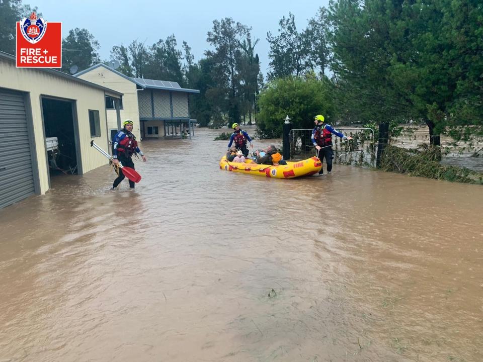 A photo of Fire and Rescue NSW crew helping residents in flood waters on the Mid North Coast.