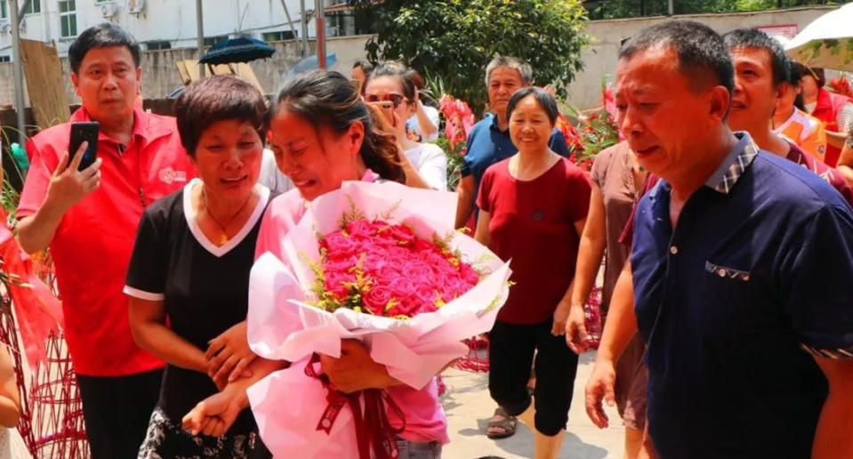 Chinese woman Jin Ting, carrying a bunch of flowers, reunited with her parents after 30 years. She went missing at the age of three.