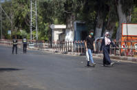 Two Palestinians wearing face masks cross a nearly empty street in Gaza City, Thursday, Aug. 27, 2020. On Wednesday Gaza's Hamas rulers extended a full lockdown in the Palestinian enclave for three more days as coronavirus cases climbed after the detection this week of the first community transmissions of the virus in the densely populated, blockaded territory. (AP Photo/Khalil Hamra)