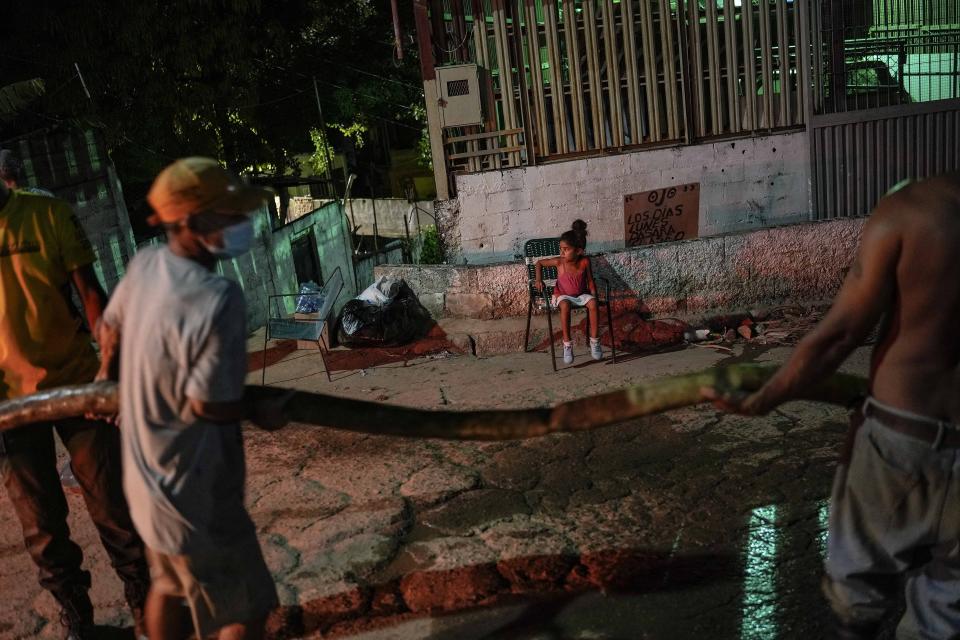 A child watches as volunteers move hoses to distribute water to residents after a deadly landslide left many homeless in Las Tejerias, Venezuela, Tuesday, Oct. 11, 2022. (AP Photo/Matias Delacroix)