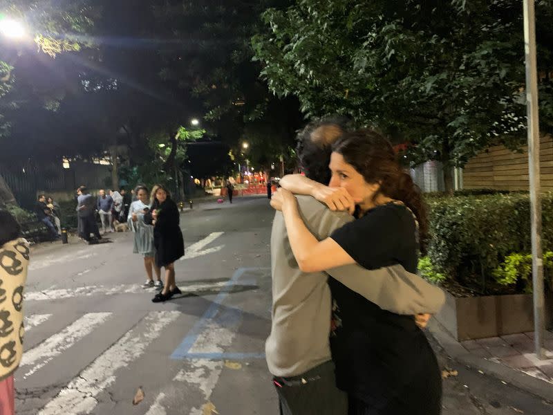 People wait outside their homes after a tremor was felt in Mexico City