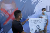 Hamas supporters hold a poster with a defaced picture of French President Emmanuel Macron during a protest against the publishing of caricatures of the Prophet Muhammad they deem blasphemous, in front of the French Cultural center in Gaza City, Tuesday, Oct. 27, 2020. (AP Photo/Adel Hana)