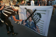 Protesters deface a picture of French President Emmanuel Macron during a protest over caricatures of the Prophet Muhammad they deem insulting and blasphemous, outside the French Embassy, in Baghdad, Iraq, Monday, Oct. 26, 2020. Muslims in the Middle East and beyond on Monday called for boycotts of French products and for protests over the caricatures, but France's president has vowed his country will not back down from its secular ideals and defense of free speech. (AP Photo/Khalid Mohammed)