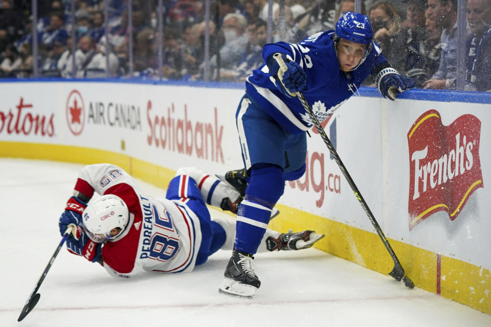 Montreal Canadiens forward Mathieu Perreault (85) falls to the ice after checking Toronto Maple Leafs defenseman Travis Dermott (23) during the first period of an NHL hockey game Wednesday, Oct. 13, 2021, in Toronto. (Evan Buhler/The Canadian Press via AP)