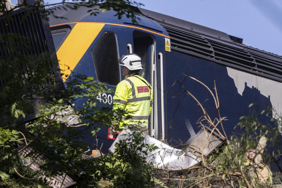Emergency services attend the scene of a derailed train in Stonehaven, Scotland, Wednesday Aug. 12, 2020. Police and paramedics were responding Wednesday to a train derailment in northeast Scotland, where smoke could be seen rising from the site. Officials said there were reports of serious injuries. The hilly area was hit by storms and flash flooding overnight. (Derek Ironside/Newsline-media via AP)