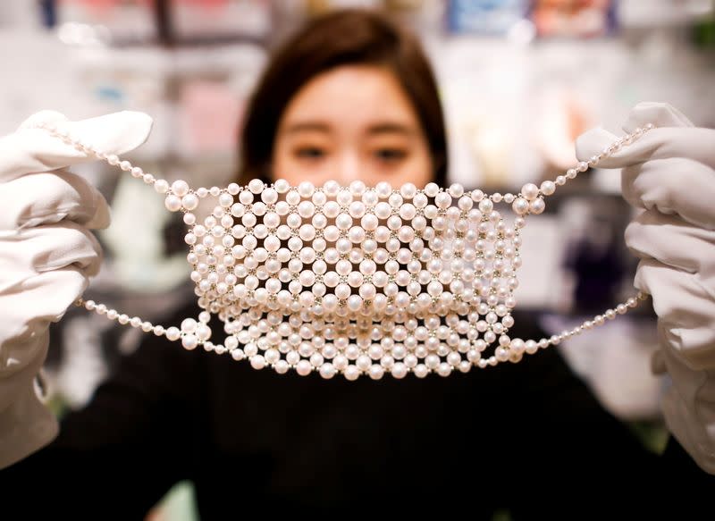 An employee of Cox Co, the operation company of the face-mask speciality shop Mask.com, shows off a luxury face mask made with about 330 pearls, in Tokyo