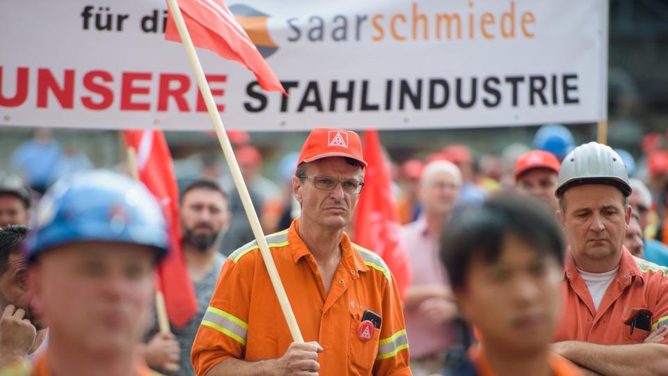 Mitarbeiter von Saarstahl stehen während einer Kundgebung auf dem Gelände von Saarstahl in Völklingen (Saarland). Foto: Oliver Dietze