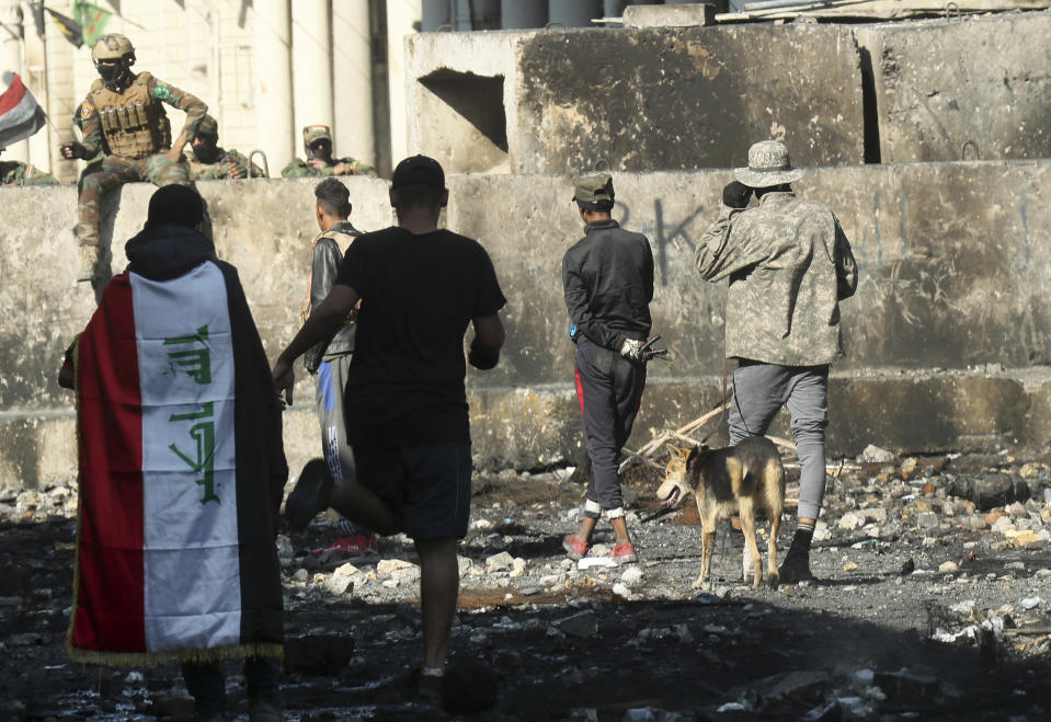 Iraqi security forces and anti-government protesters rest after both sides shake hands and converse in a rare moment of calm in hostilities called to allow time for rest after clashes in Baghdad, Iraq, Saturday, Nov. 30, 2019. (AP Photo/Hadi Mizban)