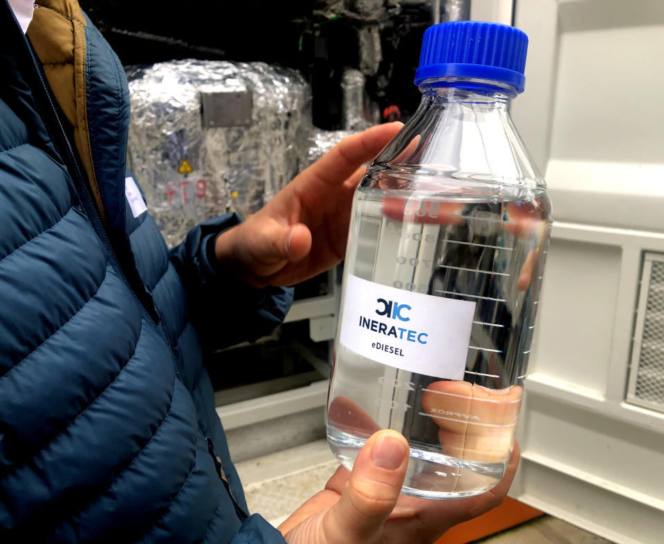 A person holds a bottle with e-fuel at the 'Atmosfair' synthetic kerosene plant in Werlte, Germany, Monday, Oct. 4, 2021. German officials are unveiling a facility in Werlte, near Germany's northwestern border with the Netherlands, what they say will be the world's first commercial plant for making synthetic kerosene as part of an effort to reduce the climate impact of flying. (AP Photo/Aleksandar Furtula)