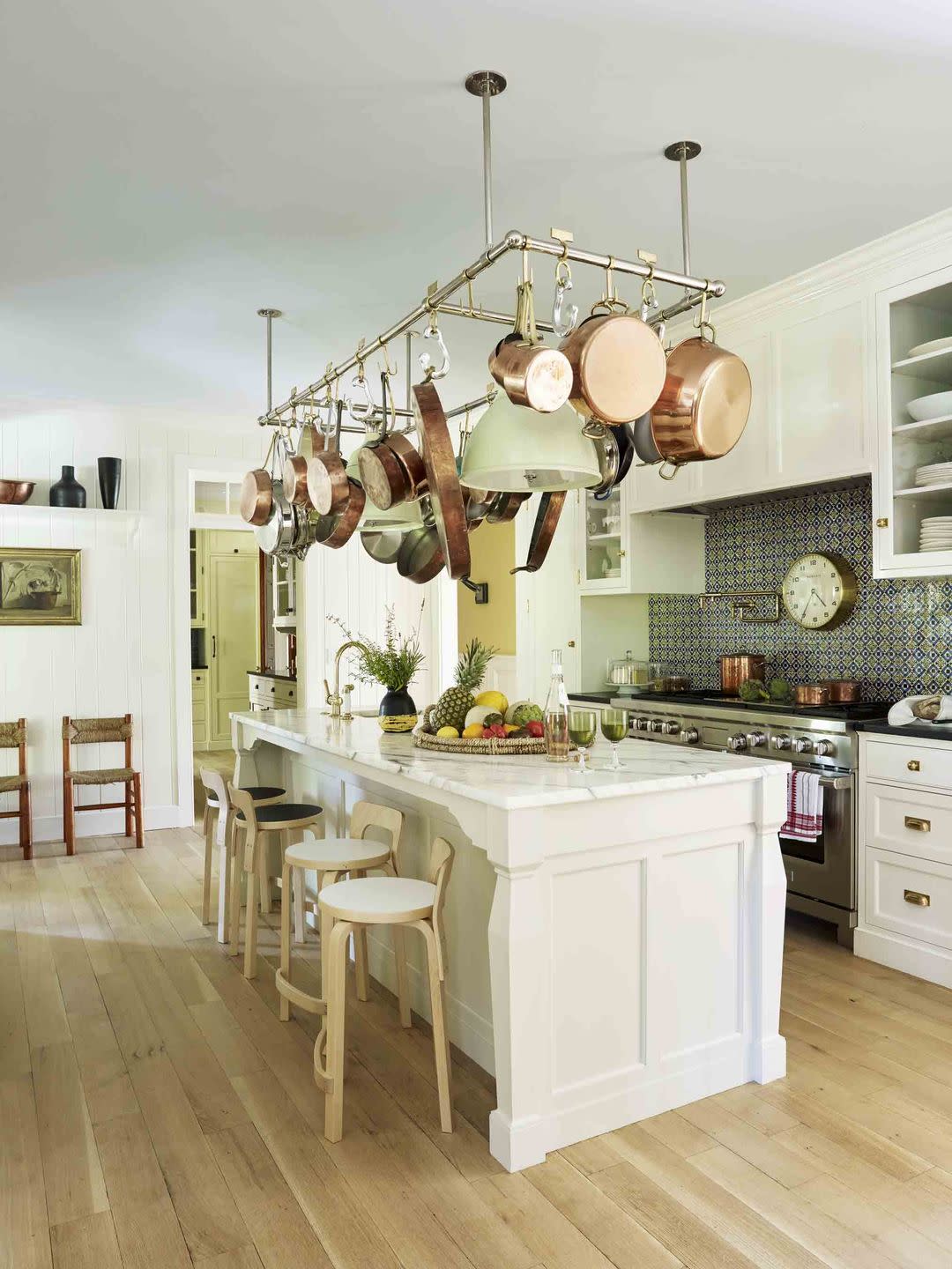 a white kitchen with a large island with a pot rack hanging over it