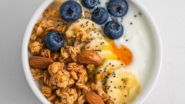 yogurt with oat, granola, nuts, and blueberries in bowl