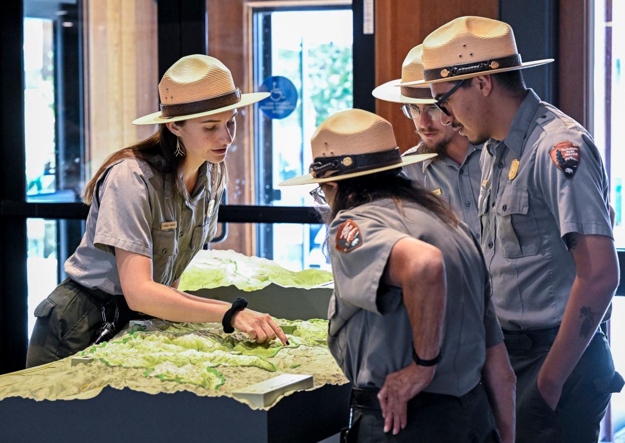 Ranger Morgan Hawkins, left, and coworkers look at a 3D map on Aug. 4, 2023, after a ribbon cutting event in Sequoia National Park for the redesigned Lodgepole Visitor Center.