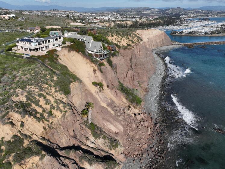 Dana Point, CA - February 13: An aerial view of three large homes in Dana Point are in danger of falling into the ocean after a cliffside gave way over the weekend after recent heavy rains in Dana Point Tuesday, Feb. 13, 2024. The double A-frame mansion was awarded the 39th spot on Dana Point's Historic Resources Register. The estate-style homes all sit along Scenic Drive where the remnants of a large chunk of land is visible at the base of the cliff. The estate-style homes all sit along Scenic Drive. (Allen J. Schaben / Los Angeles Times)