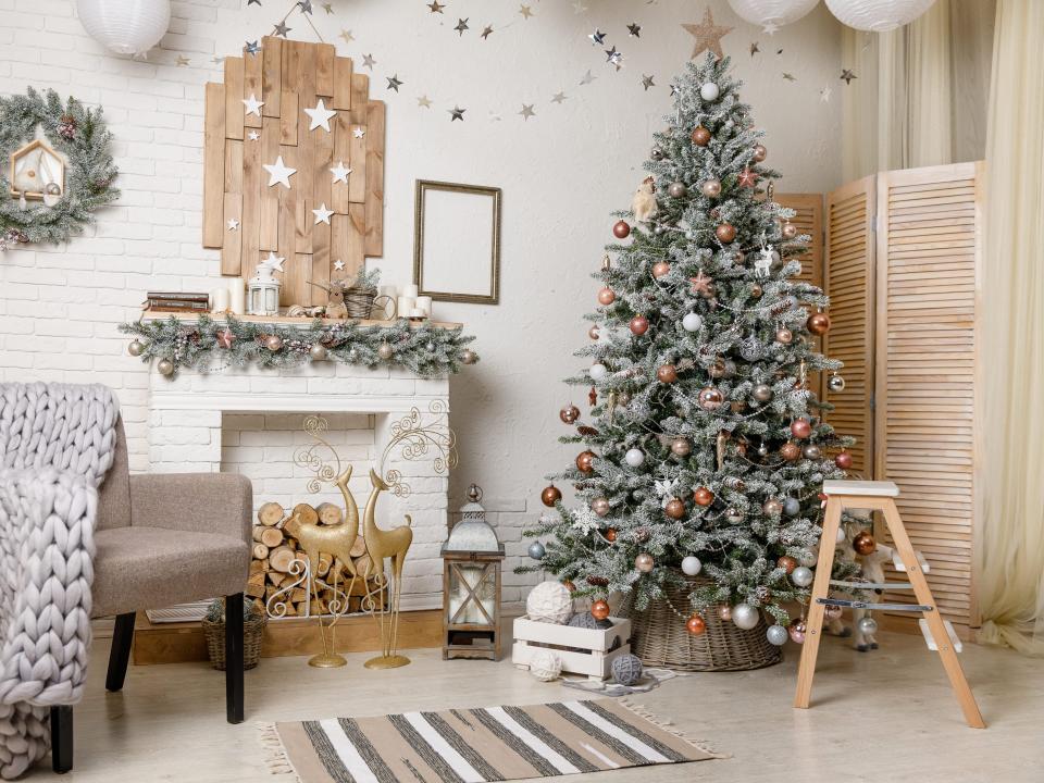 The Scandinavian style Christmas or New Year background: Christmas tree by the fireplace, pink glass balls and toys, wooden decoration, wool blanket, floor lamp
