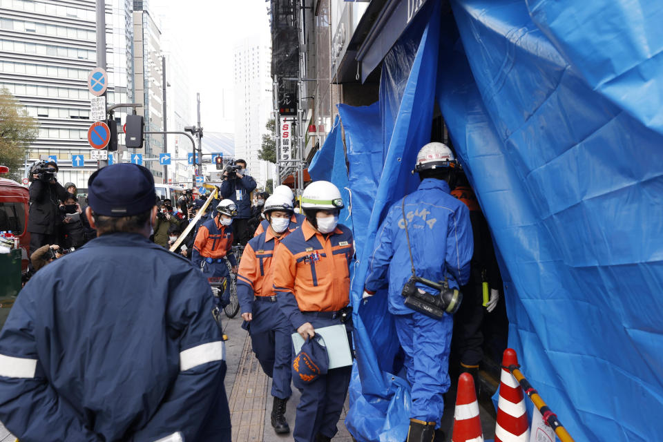 Investigators enter into a building where a fire broke out in Osaka, western Japan Saturday, Dec. 18, 2021. A fire that spread from a fourth-floor mental clinic in the eight-story building in downtown Osaka on Friday left more than 20 dead in what police were investigating as a possible case of arson and murder. (Yukie Nishizawa/Kyodo News via AP)