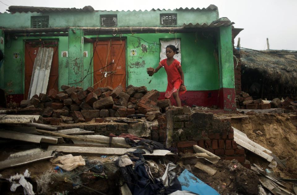 A girl removes debris from her damaged house after Cyclone Phailin hit Puri