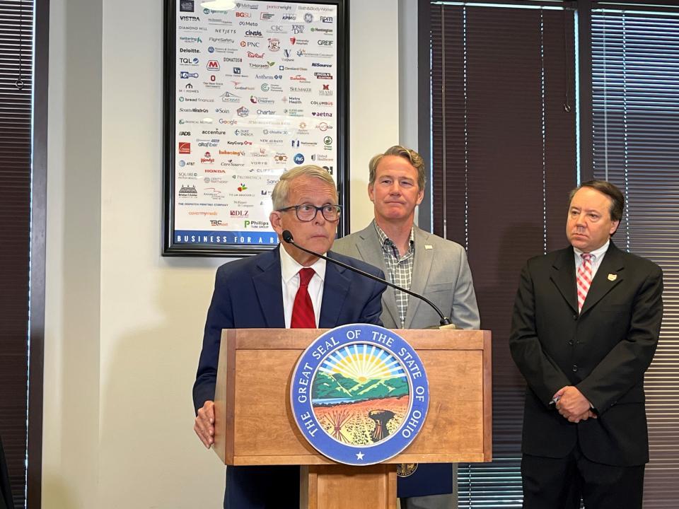 Gov. Mike DeWine stands at a podium to address Ohio workforce needs along with Lt. Gov. Jon Husted and Ohio Business Roundtable President and CEO Pat Tiberi, right. The three pushed for several of DeWine's budget proposals on Monday June 5, 2023.