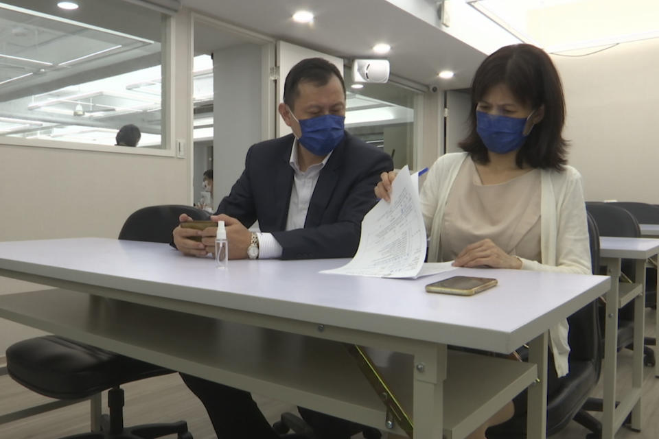 Jason Ding at left and Nancy Chen look over paperwork for national compensation case at a meeting for families who lost their loved ones to COVID-19 on Sept. 17, 2021, Taipei, Taiwan. The island is hailed globally as a pandemic success story. But for Chen and other families who lost loved ones, they are angry that their government did not prepare enough and they don't believe it's a success. (AP Photo/Johnson Lai)