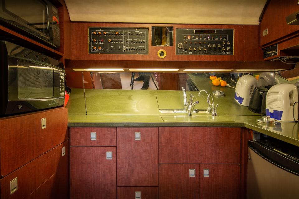 The small kitchen inside the 727 with green countertops, sink, fridge, and two ovens.