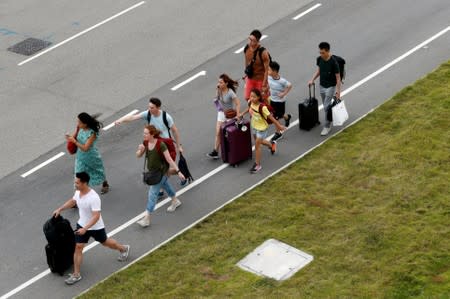 Passengers try to get to the airport as anti-extradition bill protesters block the highway leading to it, in Hong Kong