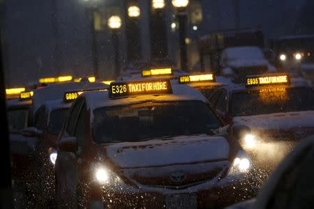 Taxis wait for fares in the snow at Union Station in Washington January 22, 2016. REUTERS/Jonathan Ernst