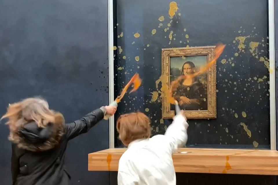 <p>DAVID CANTINIAUX/AFPTV/AFP via Getty </p> Protesters throw soup at the "Mona Lisa"