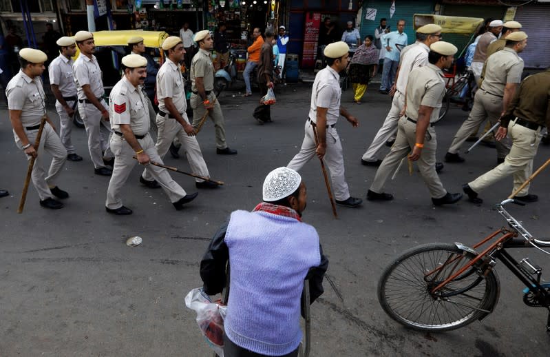 A Muslim man looks on as police officers conduct a flag march in a street outside Jama Masjid, before Supreme Court's verdict on a disputed religious site claimed by both majority Hindus and Muslim in Ayodhya, in the old quarters of Delhi