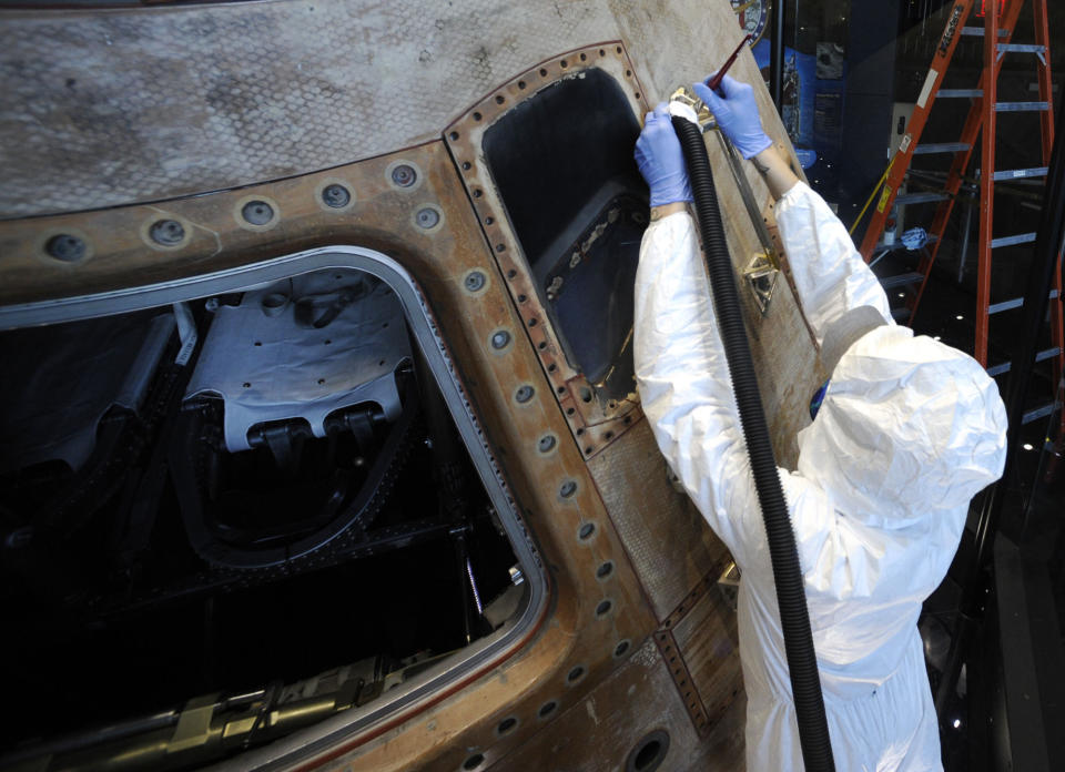 Gary Phillips uses a brush and a vacuum to clean the Apollo 16 lunar spacecraft at the U.S. Space and Rocket Center in Huntsville, Ala., on Tuesday, Feb. 1, 2022. Following a break in routine maintenance because of the COVID-19 pandemic, the museum is sprucing up the antique spaceship before events marking the 50th anniversary of its flight in 1972. (AP Photo/Jay Reeves)