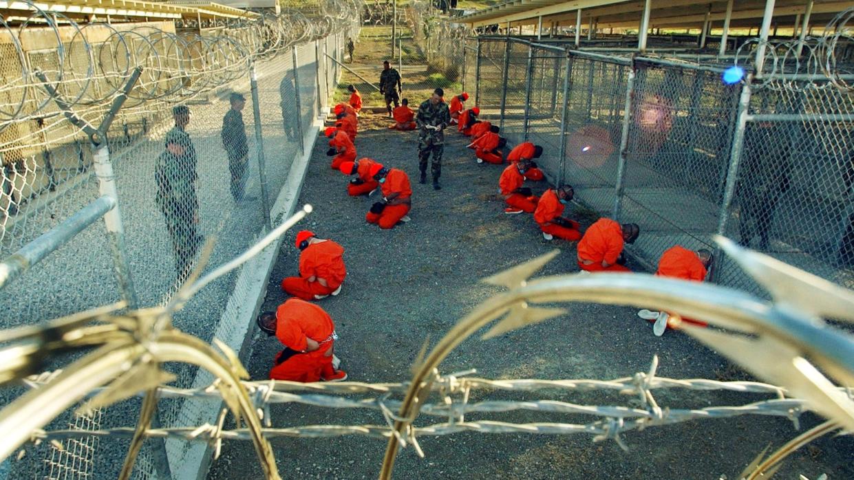  Al-Qaida and Taliban detainees kneel in orange jumpsuits at Camp X-Ray at Guantanamo Bay in 2002. 