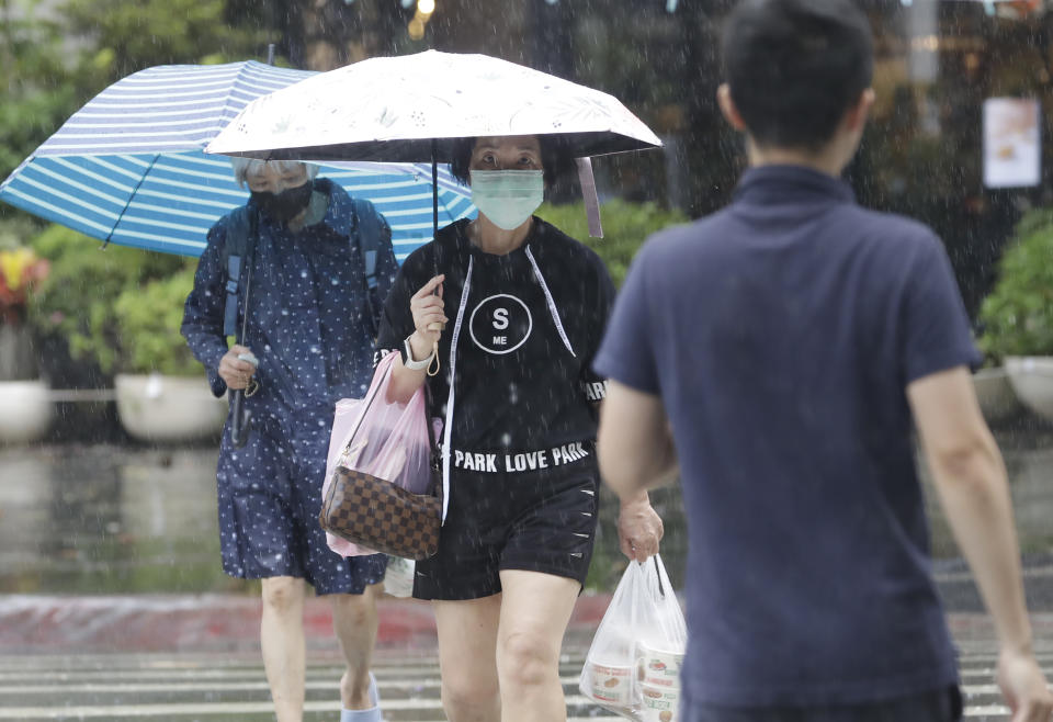 People go out shopping in the wind and rain caused by Typhoon Khanun in Taipei, Taiwan, Thursday, Aug. 3, 2023. The typhoon that damaged homes and knocked out power on Okinawa and other southern Japanese islands this week was slowly moving west Thursday but is forecast to make a U-turn and dump even more rain on the archipelago. (AP Photo/Chiang Ying-ying)
