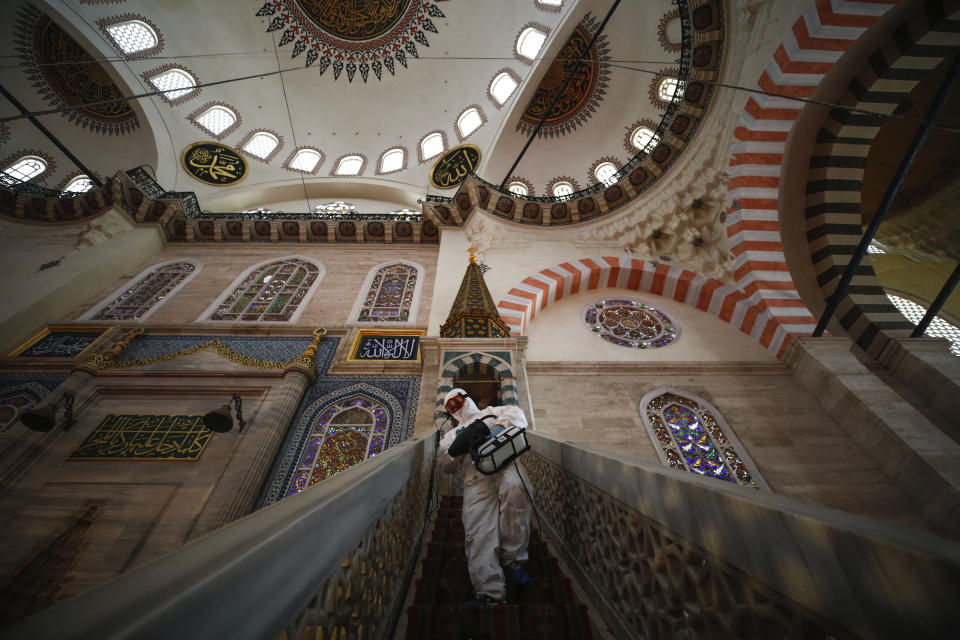 A municipality worker, wearing a protective suit against the coronavirus, disinfects the historical Suleymaniye Mosque, in Istanbul, during the third day of Eid el-Fitr and the last day of a four-day curfew due to the outbreak, Tuesday, May 26, 2020. Istanbul's municipality workers disinfected several mosques which were locked down for more than six weeks and will be partly open again for prayers on Friday, May 29. The Muslim holiday marking the end of the fasting month of Ramadan, traditionally a time of gathering, was marked by a nationwide lockdown to combat the coronavirus. (AP Photo/Emrah Gurel)