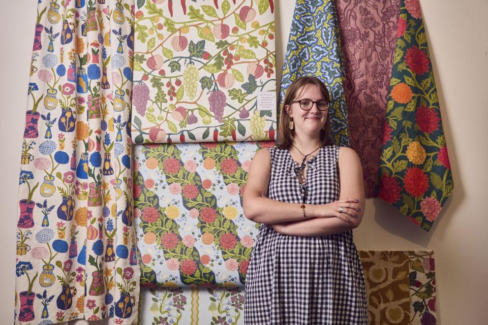 a designer standing in front of hanging textiles