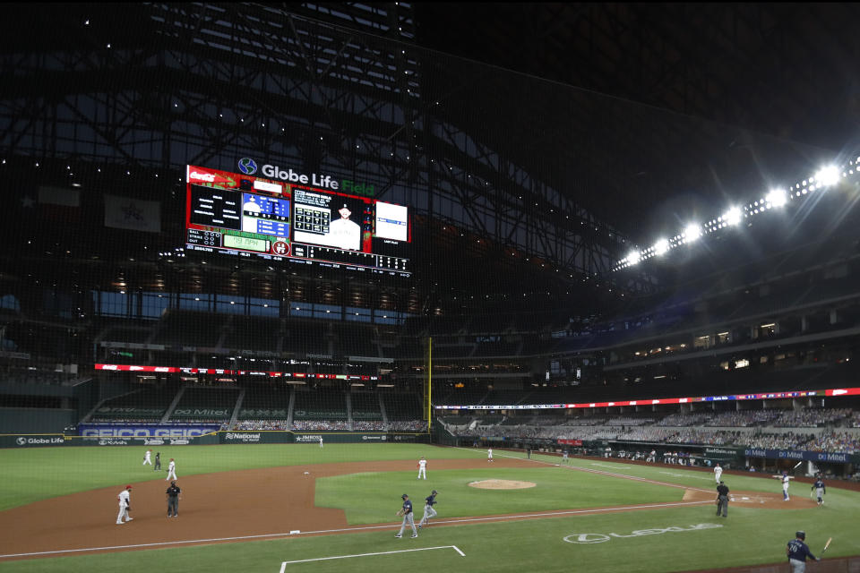 Seattle Mariners third base coach Manny Acta, bottom center left, celebrates with Austin Nola, bottom center right, who trots home after hitting a solo home run against the Texas Rangers in the second inning of a baseball game in Arlington, Texas, Wednesday, Aug. 12, 2020. (AP Photo/Tony Gutierrez)