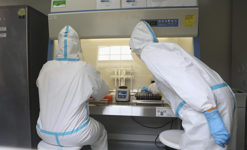 Health workers analyze samples collected during mass coronavirus testing inside a mobile laboratory in Jakarta, Indonesia, Thursday, June 18, 2020. (AP Photo/Achmad Ibrahim)