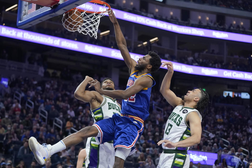 Golden State Warriors forward Andrew Wiggins, center, dunks between Milwaukee Bucks forward Giannis Antetokounmpo, left, and forward Jordan Nwora (13) during the first half of an NBA basketball game in San Francisco, Saturday, March 12, 2022. (AP Photo/Jeff Chiu)