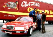 <p>He could make any car look iconic. Here he poses with Jim Nabors and Hal Needham during the filming of <em>Stroker Ace </em>in 1982 at the Lakewood Park Speedway in Atlanta.</p>