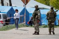 Service members of pro-Russian troops stand guard near a temporary accommodation centre in Bezimenne