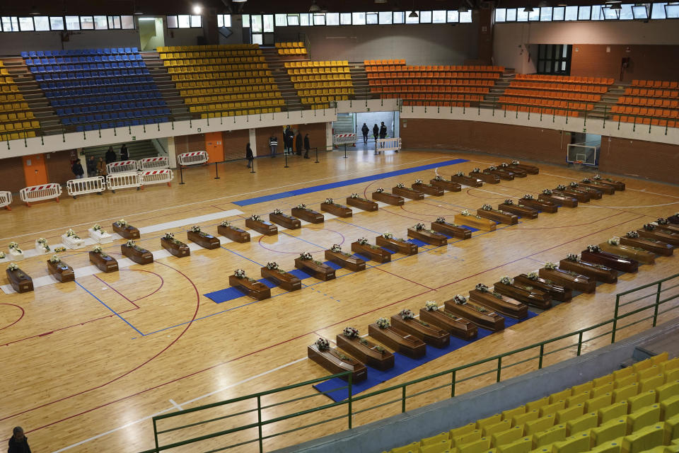 The coffins of the victims of last Sunday's shipwreck are lined up at the local sports hall in Crotone, southern Italy, Tuesday, Feb. 28, 2023. At least 65 people, including 14 minors, died when their overcrowded wooden boat slammed into shoals 100 meters (yards) off the shore of Cutro and broke apart early Sunday in rough seas. Eighty people survived, but many more are feared dead since survivors indicated the boat had carried about 170 people when it set off last week from Izmir, Turkey. (Antonino D'Urso/LaPresse via AP)