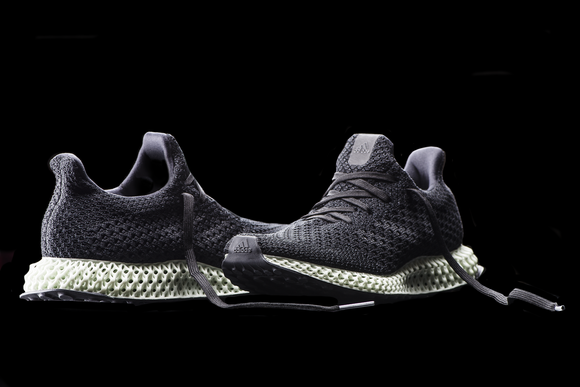 A pair of adidas' Futurecraft 4D running shoes -- dark-colored uppers, light-colored and lattice-shaped midsoles, with a black background.