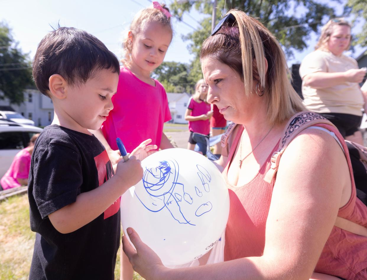 Zachary Fornash's son, 3-year-old Elijah, and his sister Avah, 6, sign and draw on balloons for their father, Zachary Fornash, who was shot and killed by a Canton police officer in 2023. Their aunt Kim Billman helps them prior to a balloon launch commemorating Fornash's 25th birthday.